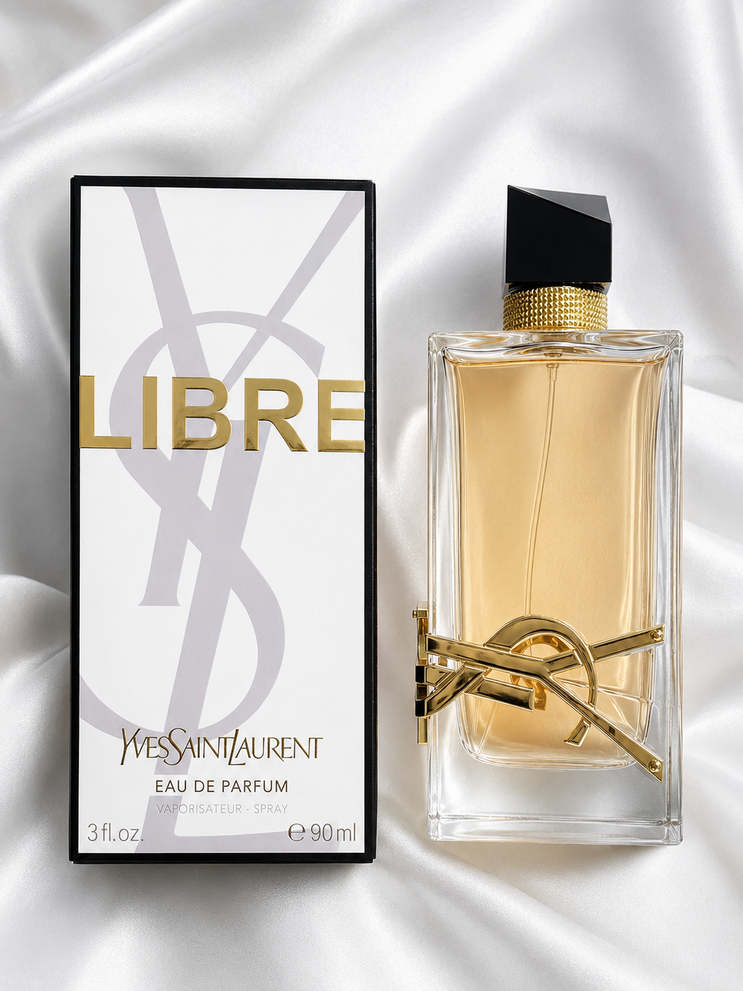 Yves Saint Laurent Libre Eau de Parfum bottle and its packaging box, displayed on a draped white satin fabric background.